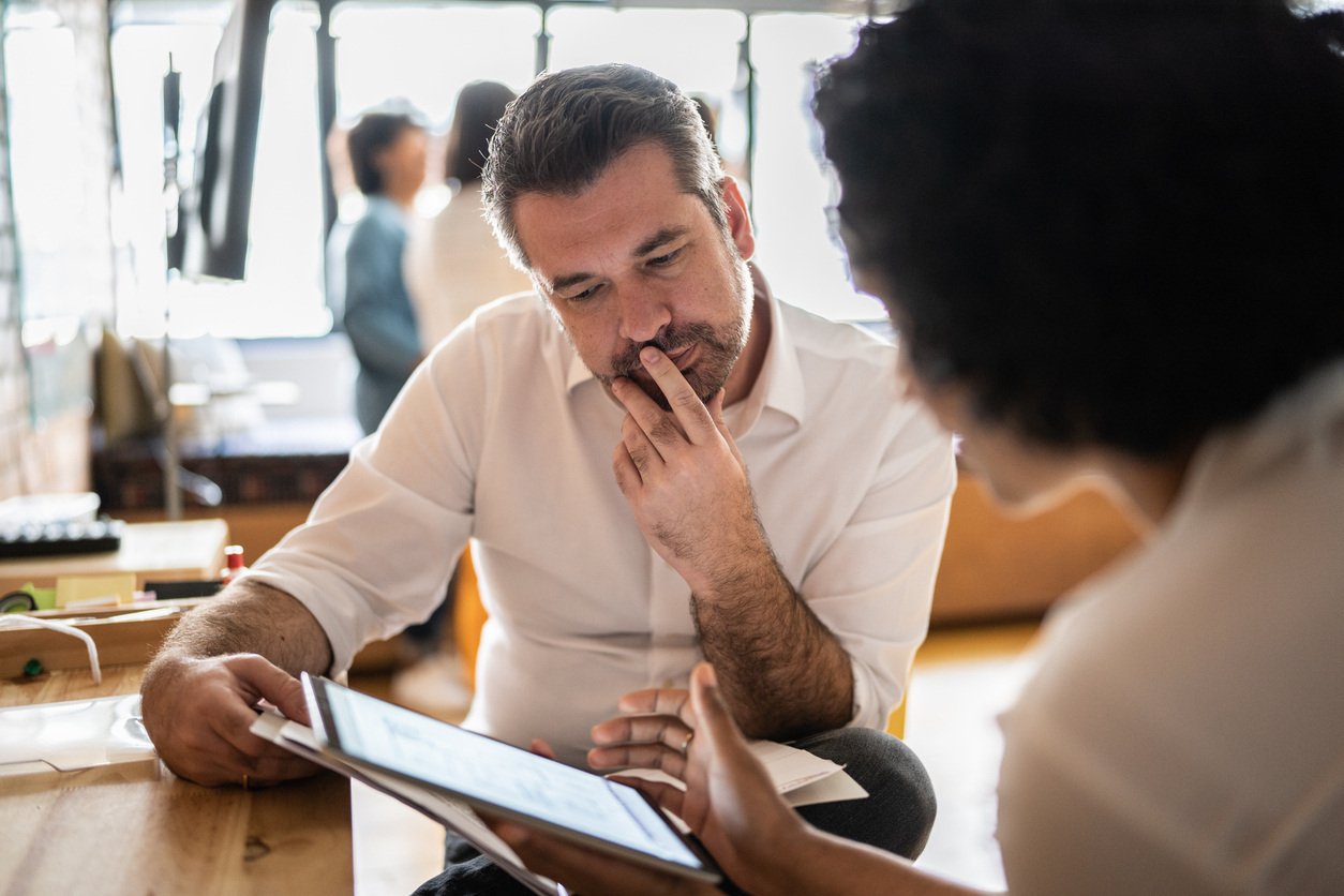 man and woman discussing key metrics from an ipad in business